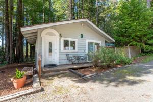 a small white shed with a porch and a table at Green Tree Cottage in Mendocino