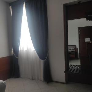 a room with a curtain and a mirror next to a bed at Best Western Hotel Nettuno in Brindisi +39 photos