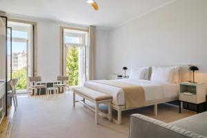 a white bedroom with a large bed and a balcony at Rosário Suites Townhouse in Porto