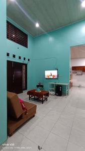 a living room with a couch and a tv on a wall at Homestay Karimun in Grogol