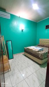a bedroom with a bed and a blue wall at Homestay Karimun in Grogol