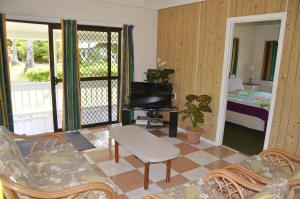 a living room with a television and a room with a bed at Flame Cottage in Rarotonga