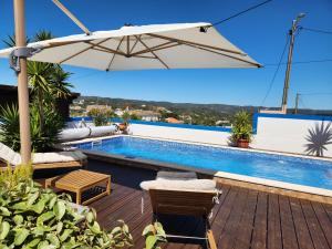 a swimming pool with an umbrella and chairs next to a pool at Casa Bella Studio in São Brás de Alportel