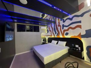 a bedroom with a bed with a painting on the wall at Blue Suítes - motel in Cascavel +28 photos