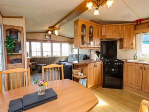 a kitchen with wooden cabinets and a wooden table at The Granada at Argraig in Holyhead