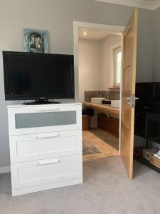 a living room with a television on a white dresser at The Annexe in Kirkcudbright