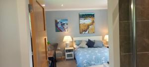 a bedroom with a bed and three paintings on the wall at The Annexe in Kirkcudbright