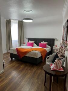 a bedroom with a bed with pink pillows and a table at Landhaus Hotel Neuss in Neuss
