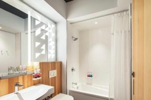 a bathroom with a tub and a toilet and a sink at Alt Hotel Ottawa Airport in Ottawa +26 photos