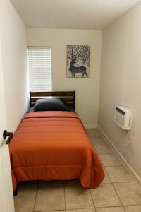 ein Schlafzimmer mit einem Bett mit einer orangefarbenen Decke in der Unterkunft Cabana in Miami + 1 Foto