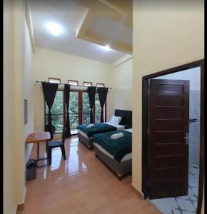 a bedroom with two beds and a table and a window at The Sanduk Inn in Rantepao