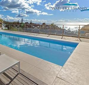 a swimming pool with blue water in a building at Hot Tub Seaview Chalet 12 in Waiheke Island