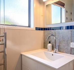 a bathroom with a sink and a mirror and a window at Hot Tub Seaview Chalet 12 in Waiheke Island +13 photos