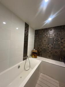 a white bath tub in a bathroom with a tile wall at Appartement premium Hyper Centre in Ajaccio +17 photos