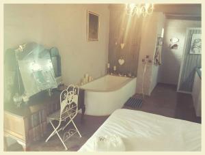 - une chambre avec une baignoire, un lit et une chaise dans l'établissement Die Woestynroos Gastehuis, à Isidule