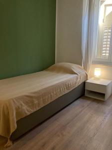 a green bedroom with a bed and a table with a lamp at Casa Dante in Gradisca dʼIsonzo