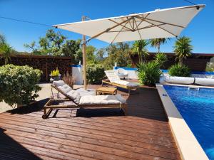 a wooden deck with chairs and an umbrella next to a swimming pool at Casa Bella Studio in São Brás de Alportel