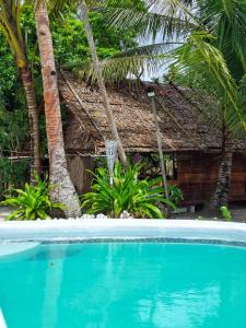 a swimming pool in front of a house with palm trees at Manoa Kei Boutique Villas in Letman