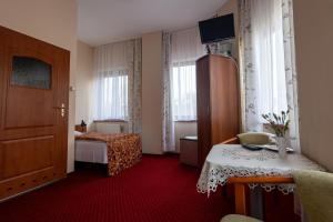 a hotel room with a bedroom with a bed and a table at Hotel Anka in Słubice