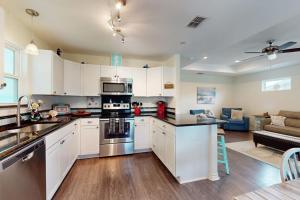 a kitchen with white cabinets and a living room at South Pearl Sailfish in Rockport