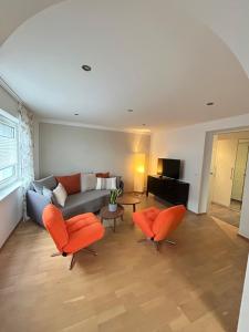 a living room with orange chairs and a couch at MühlengasseONE in Lenzing