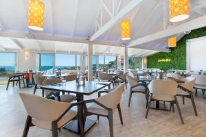 a dining room with tables and chairs and windows at Hot Tub Seaview Chalet 12 in Waiheke Island