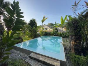 a swimming pool in the middle of a garden at Foozoo Mantra Weligama in Weligama