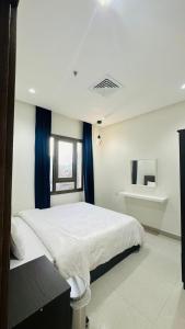 a bedroom with a large white bed with blue curtains at Noble Rose Apartment in Kuwait