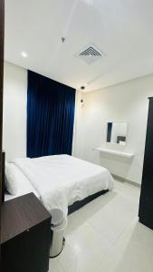 a bedroom with a white bed and a blue curtain at Noble Rose Apartment in Kuwait