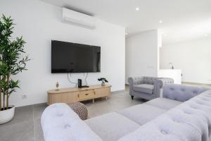 a living room with two couches and a flat screen tv at Lusomare By Marenssa in Moncarapacho