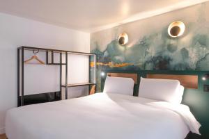 a bedroom with a white bed and a painting at Kyriad Argenteuil in Argenteuil