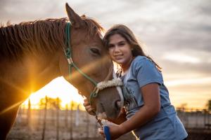 a girl hugging a horse in front of the sunset at Tarentaal Guest Farm Etosha National Park Namibia in Okaukuejo
