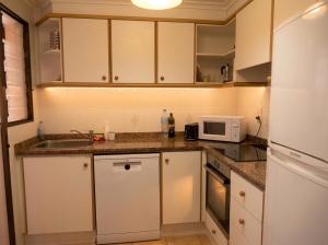 a kitchen with white cabinets and a sink and a microwave at Apartamento en Xeraco in Xeraco