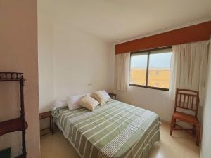 a bedroom with a bed and a window and a chair at Apartamento en Xeraco in Xeraco