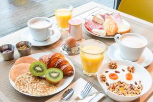 a table topped with plates of breakfast foods and drinks at Kyriad Argenteuil in Argenteuil +17 photos