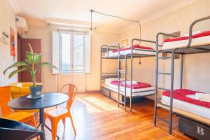 a room with three bunk beds and a table at Ostello Bello Roma Colosseo in Rome