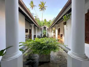 a courtyard of a house with columns and plants at Foozoo Mantra Weligama in Weligama