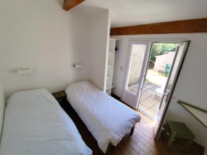 two beds in a small room with a window at Village Vacances La Manne in Bormes-les-Mimosas