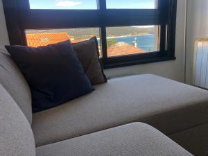 a couch sitting in a room with a window at Refugio climático en Finisterre frente a la playa con vistas al mar!! in Fisterra
