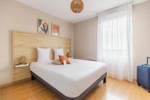 a bedroom with a large white bed and a window at Appart'City Confort Toulouse Aéroport Cornebarrieu in Cornebarrieu