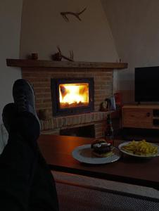a person sitting in front of a fireplace with a plate of food at La casa de Somiedo in Pola de Somiedo