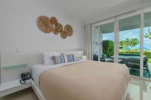 a white bedroom with a large bed and a balcony at Apartment in paradise on the happy island of ARUBA, beachfront in Savaneta +13 photos