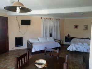 Sala de estar con 2 camas y mesa en Bungalows Esperanza del Mar en Santa Clara del Mar