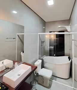 a bathroom with a sink and a toilet and a tub at Lakefront Chalet, hot tub, heated bathtub and waterfall in Alexânia +74 photos