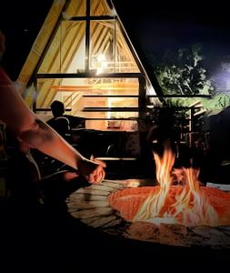 a person cooking food over a fire in a cabin at Lakefront Chalet, hot tub, heated bathtub and waterfall in Alexânia