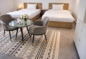a bedroom with two beds and a table and chairs at Najd APARTMENTS in Al-ʿUla +8 photos