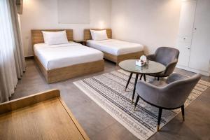 a room with two beds and a table and a chair at Najd APARTMENTS in Al-ʿUla