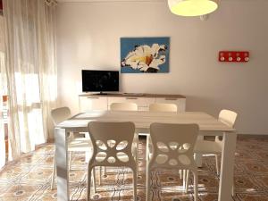 a dining room table with chairs and a television at Appartamenti Oscar in Grado