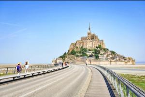 a road leading to a large building on a hill at La prairie de la baie du mont saint michel in Précey