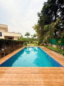 a large blue swimming pool next to a house at Mango People Farm in Gurgaon +42 photos